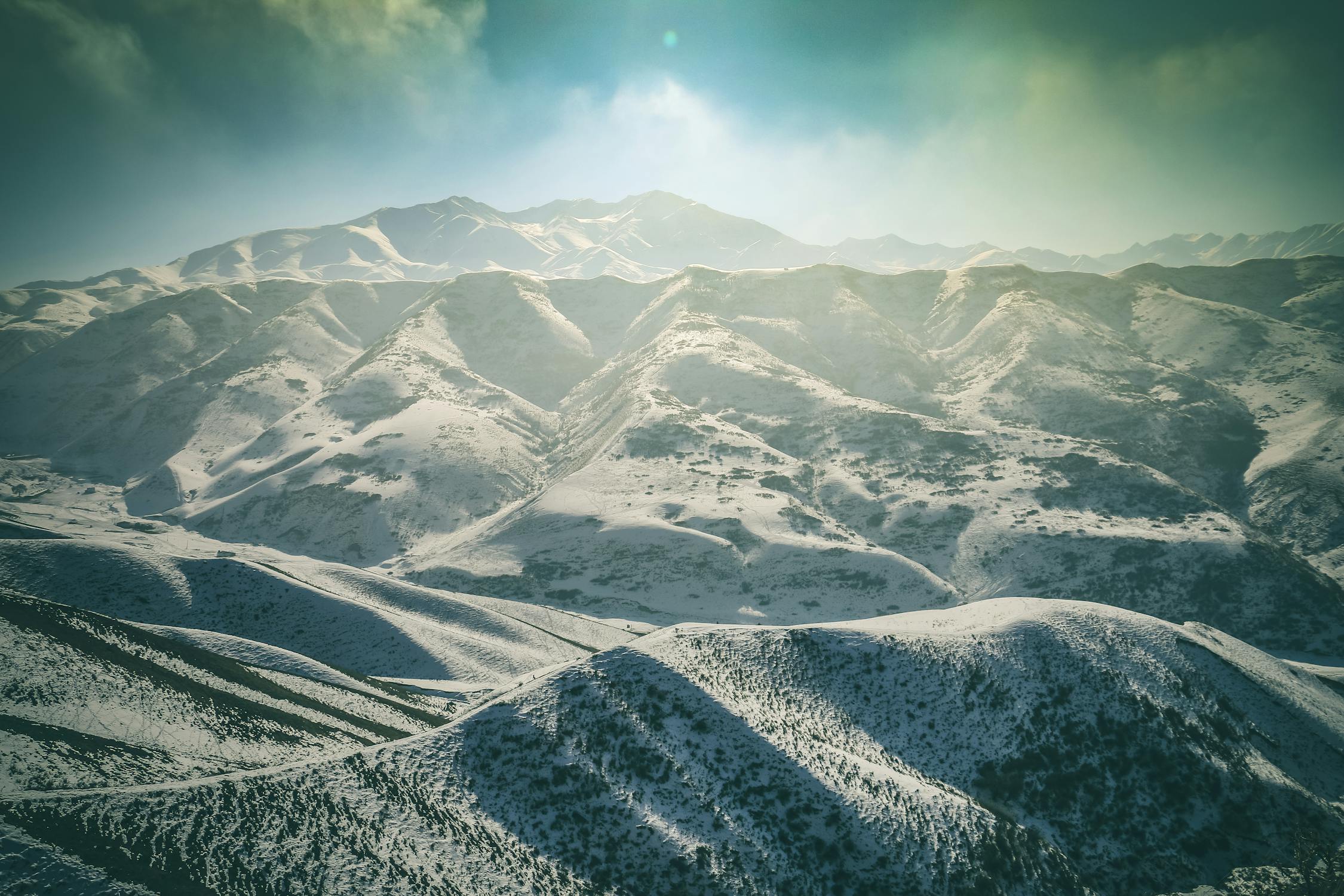 Panoramic vista of the Tian Shan mountains in Kyrgyzstan, showcasing rugged peaks and alpine meadows.