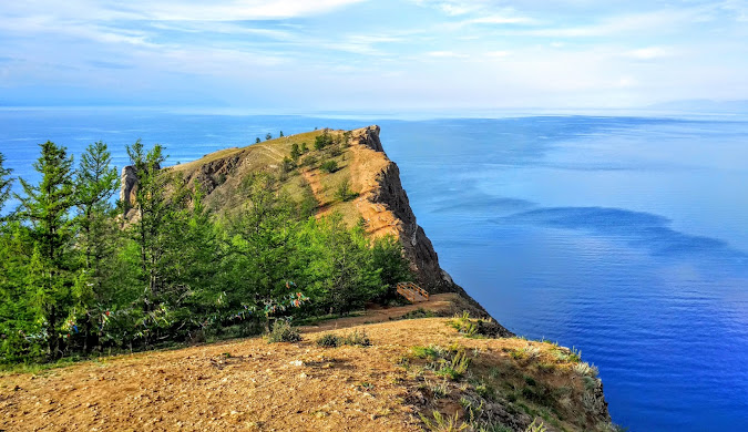 Lake Baikal in summer, showcasing its vast blue waters and surrounding Siberian taiga forests.