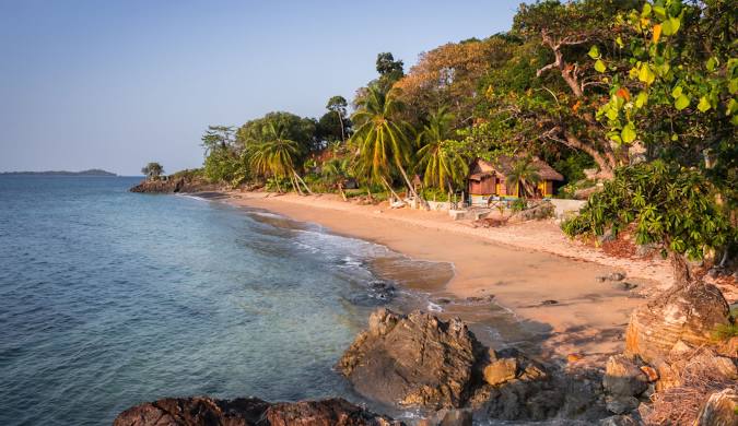 Turquoise waters lapping onto a pristine white sand beach in [Location, e.g., Nosy Be, Madagascar], with palm trees swaying in the breeze.