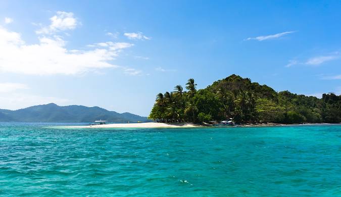 view of a Andaman Island lush, green island with a white sandy beach, surrounded by vibrant turquoise water.
