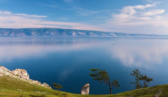 Lake Baikal in summer, showcasing its vast blue waters and surrounding Siberian taiga forests