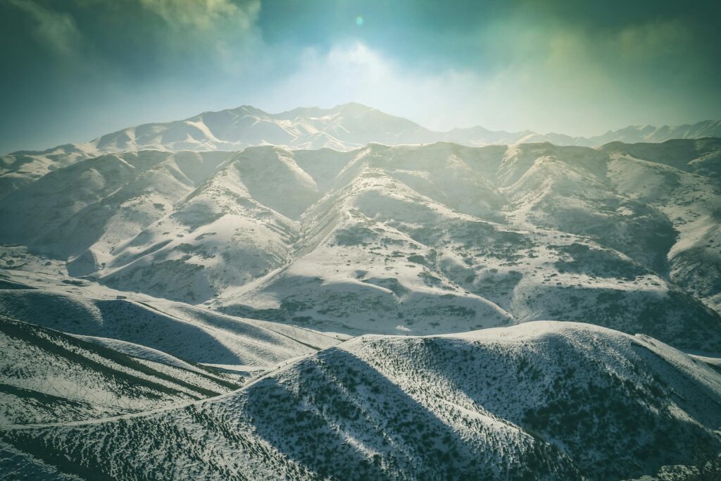 Panoramic vista of the Tian Shan mountains in Kyrgyzstan, showcasing rugged peaks and alpine meadows.