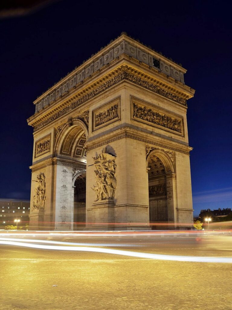 Arc de Triomphe monument in Paris illuminated at night, with traffic light streaks - latest travel blog updates.