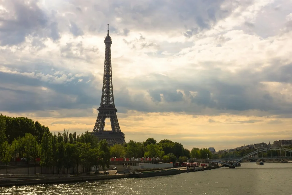 Eiffel Tower viewed from across the Seine River in Paris under a dramatic cloudy sky - Paris travel inspiration.