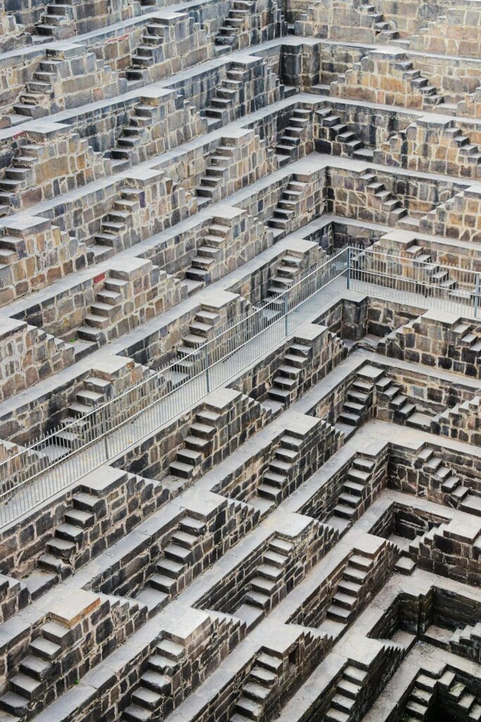 Chand Baori stepwell in Abhaneri, Rajasthan, India, showing its intricate network of steps and chambers. The ancient architecture of this water structure is highlighted in this overhead view.
