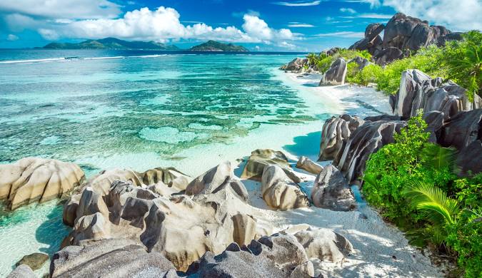 Stunning Seychelles beach scene showcasing unique granite rock formations along a white sand shore. Turquoise ocean water is crystal clear, ideal for swimming. Check our travel blog for the latest travel blog updates and discover the best time to visit Seychelles.