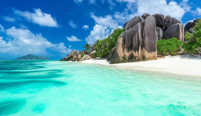 Stunning Seychelles beach scene showcasing unique granite rock formations along a white sand shore. Turquoise ocean water is crystal clear, ideal for swimming. Check our travel blog for the latest travel blog updates and discover the best time to visit Seychelles.