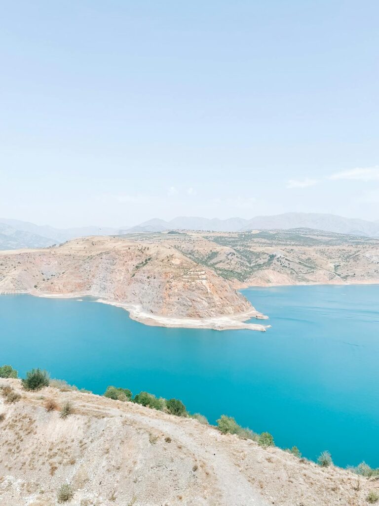 Scenic view of Charvak Lake's turquoise waters surrounded by arid hills in Uzbekistan