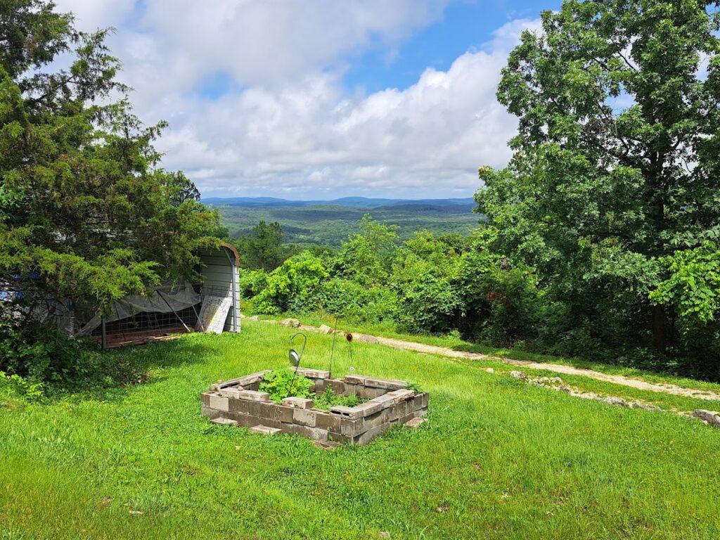 Distant view of rolling hills and a valley in the Ozark Mountains from a high point in Mark Twain National Forest. Appreciate the vastness and beauty of the Ozark landscape during your Ozark National Forest hiking and Mark Twain National Forest camping adventure.