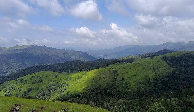 Panoramic view of the rolling green hills and valleys of Gavi, Kerala, showcasing the region's untouched natural beauty and diverse landscape.