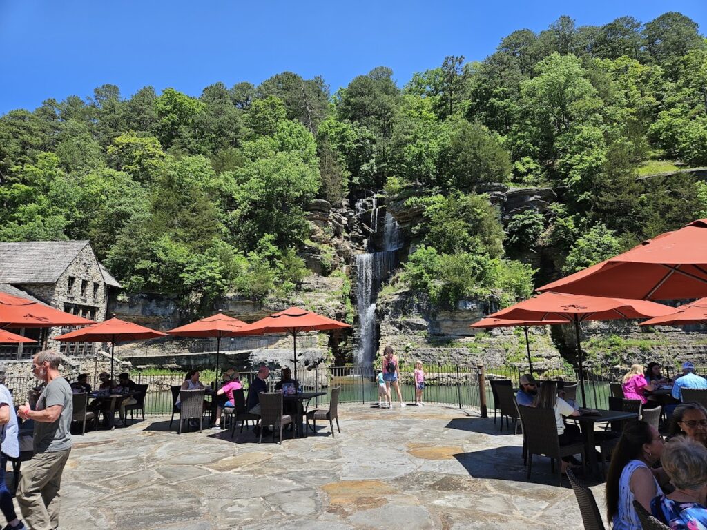 utdoor dining area with umbrellas and a waterfall backdrop at Dogwood Canyon Nature Park near Mark Twain National Forest. Enjoy dining with scenic views at attractions like Dogwood Canyon Nature Park, a great addition to your Mark Twain National Forest adventure.