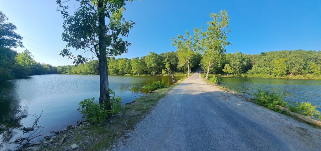 Scenic gravel road leading to a lake in Mark Twain National Forest. Explore the diverse landscapes of Mark Twain National Forest, perfect for scenic drives and accessing Missouri River rafting Ozarks adventures.