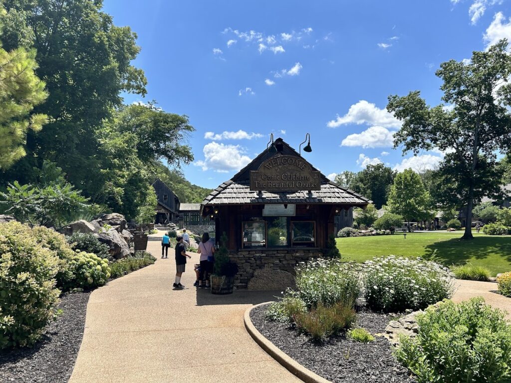 Outdoor dining area with umbrellas and a waterfall backdrop at Dogwood Canyon Nature Park near Mark Twain National Forest. Enjoy dining with scenic views at attractions like Dogwood Canyon Nature Park, a great addition to your Mark Twain National Forest adventure.