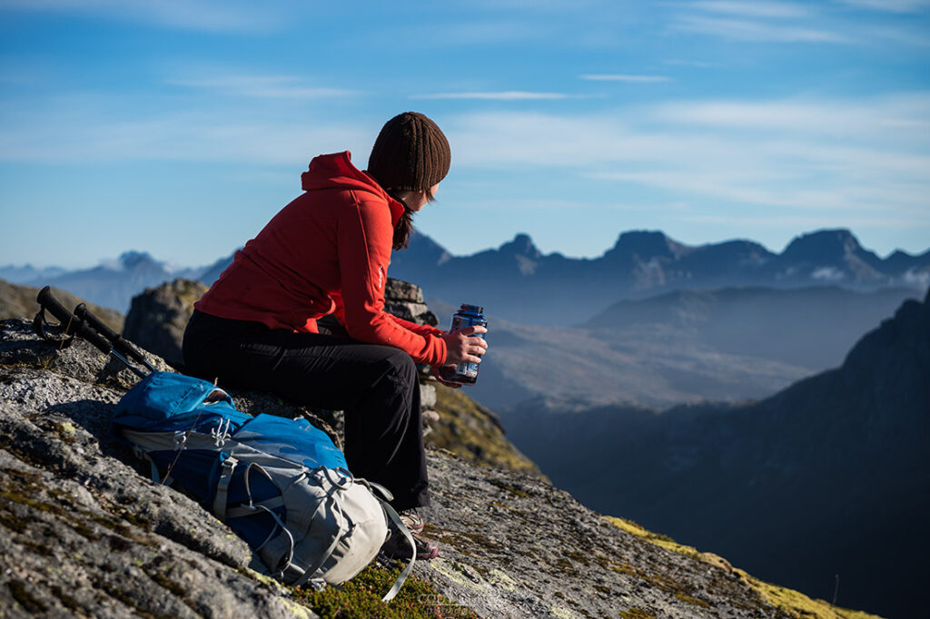 Hiker in waterproof gear trekking a trail in the Lofoten Islands, Norway