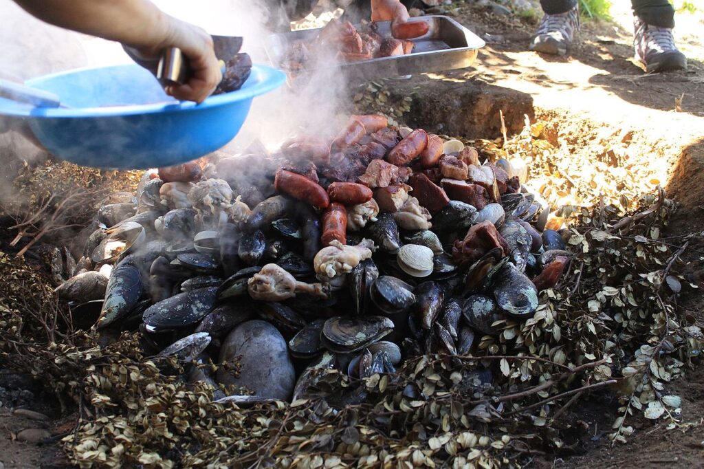 Traditional curanto dish cooked in a pit in Chiloé Island, Chile — potatoes, shellfish and meat
