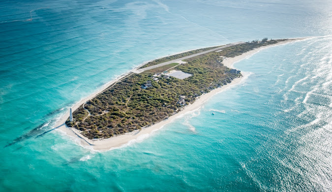 Medjumbe Island coastline with clear waters and coral reefs known for dramatic drop-offs, swim-throughs, and rich pelagic biodiversity.