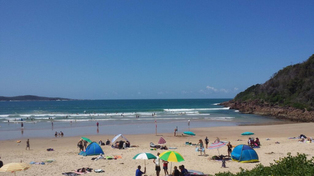 One Mile Beach offers a wilder experience with striking rocky coastline framing the surf beach.