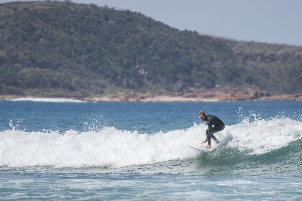 One Mile Beach offers a wilder experience with striking rocky coastline framing the surf beach.